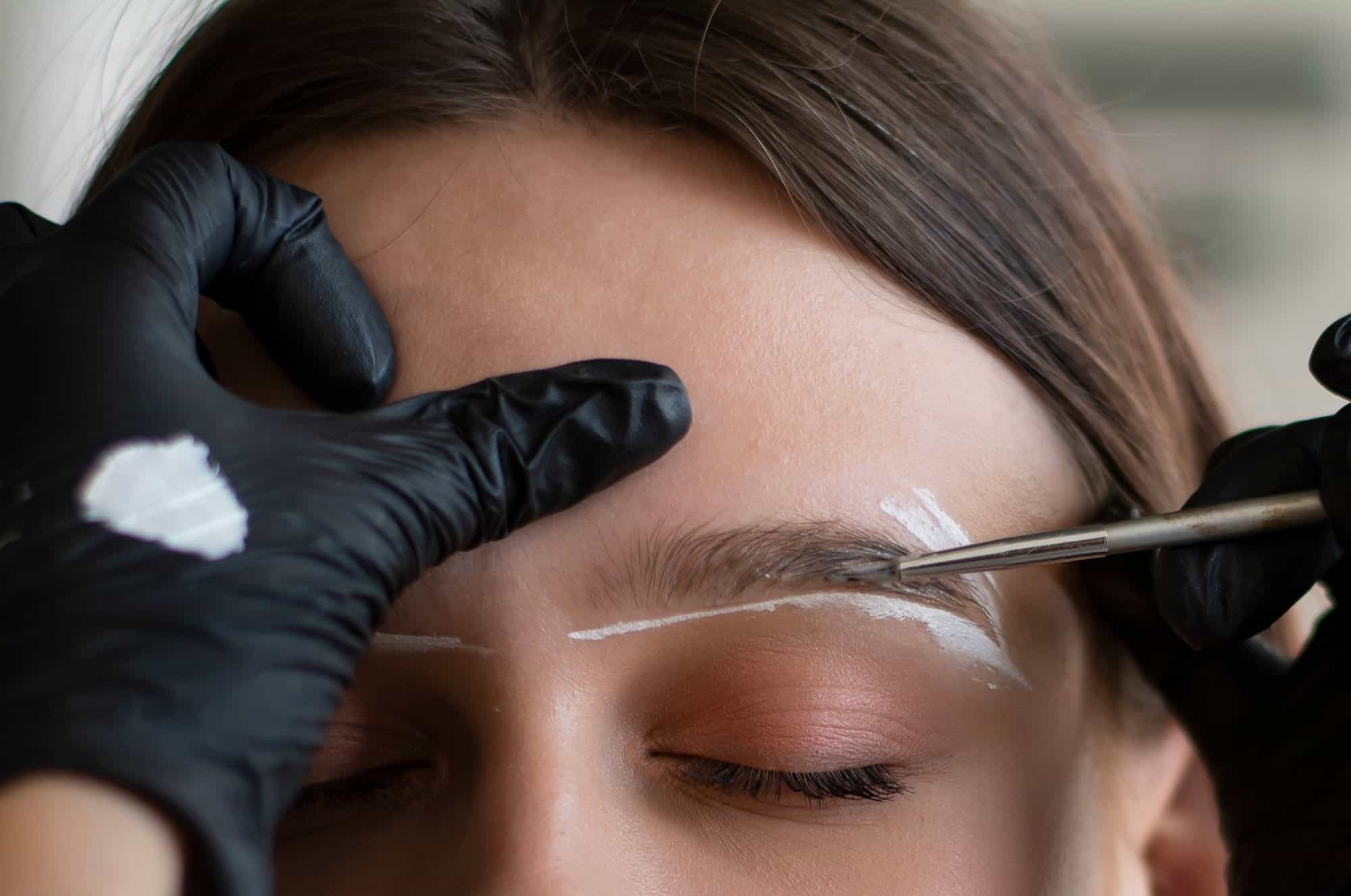 Young woman undergoing eyebrow correction procedure in beauty salon by Avia Medical Spa in the United States , closeup by Avia Medical Spa in the United States