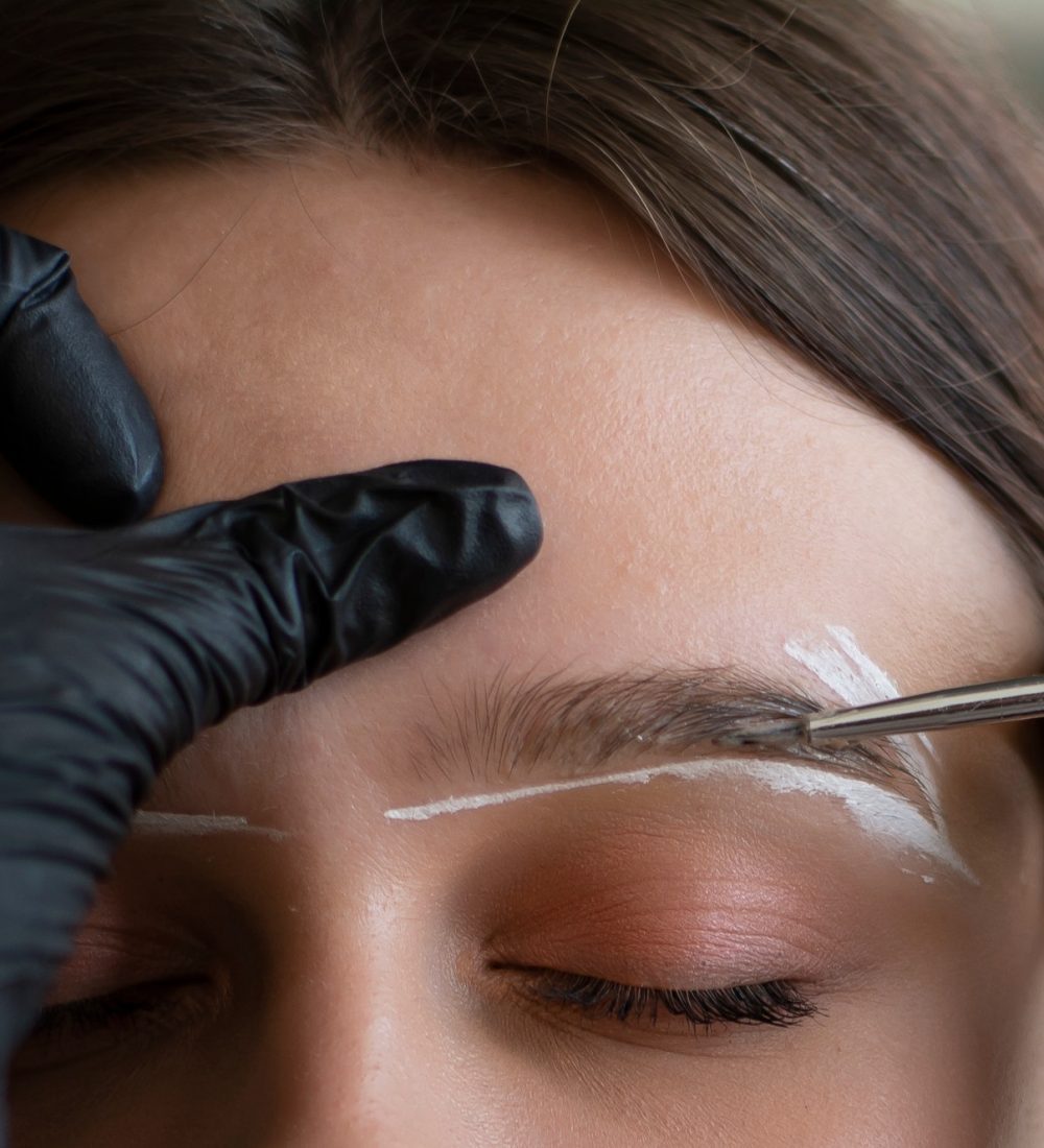 Young woman undergoing eyebrow correction procedure in beauty salon, closeup